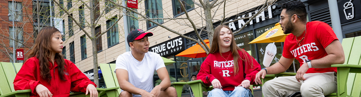 Four students sitting in green lawn chairs at The Yard